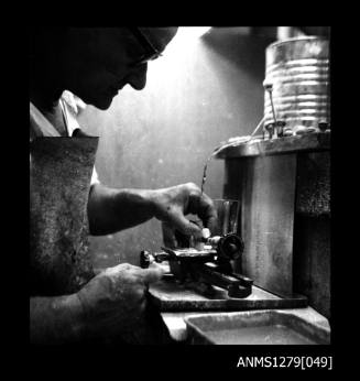 A man, possibly Denis George, using pearl making tools