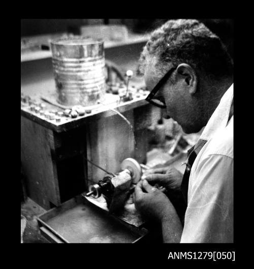 A man, possibly Denis George, using pearl making equipment