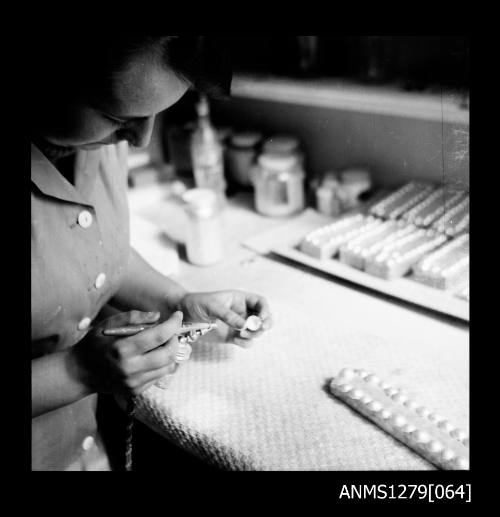 A woman spraying the inside of a half pearl (or mabe pearl) with pearl essence from an air brush