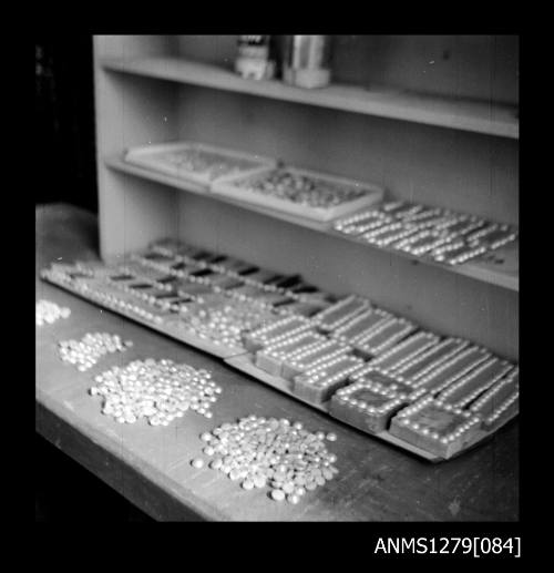 Piles of half pearls (or mabe pearls), nuclei on blocks [?] and metal trays