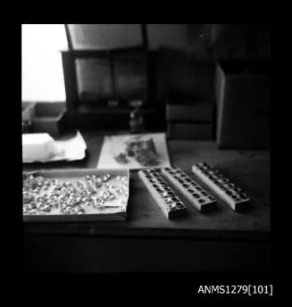 A tray of half pearls (or mabe pearls) and wooden half pearl holders (for spraying the half pearls) on a desk