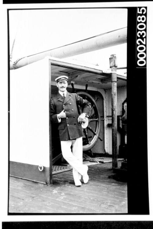 Man on deck in front of a ships wheel