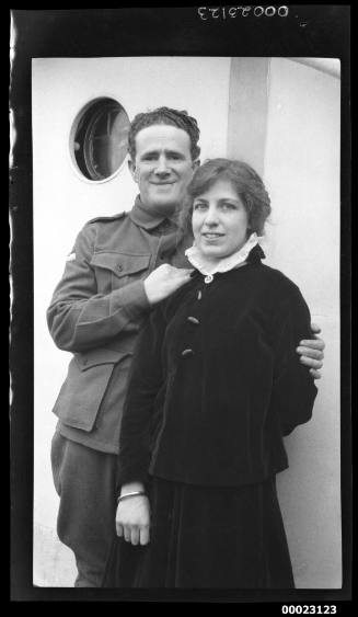 Unidentified man and woman standing near a porthole