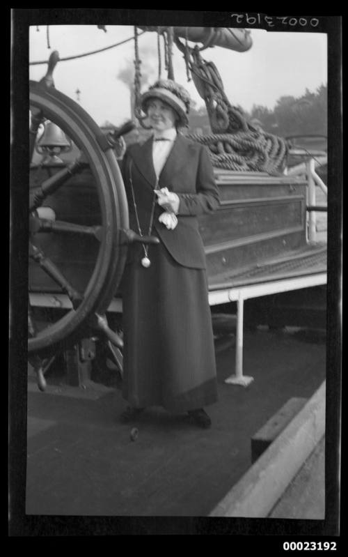 Woman standing next to ship's wheel