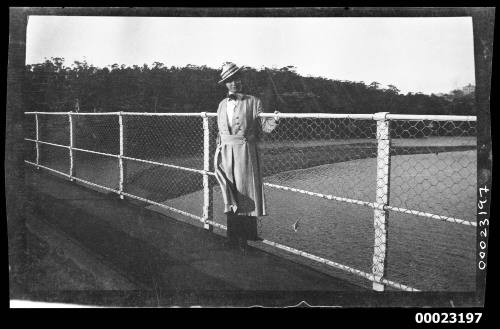 Unidentified women standing in front of a wire mesh fence