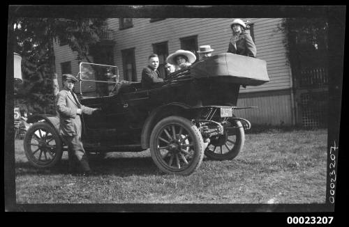 Three men and two women sitting in the back of a convertible car