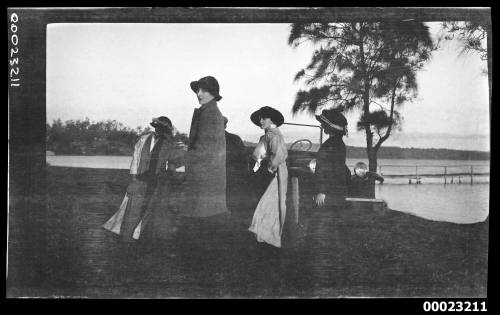 Four women and two men around a car