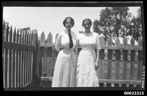 Two women in front of a picket fence