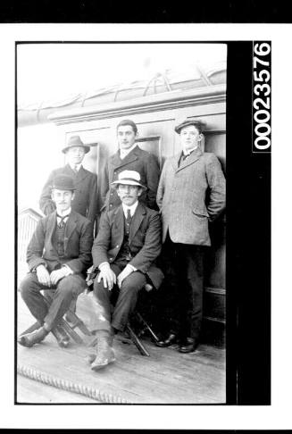 Ships and steamer crews, two men seated on stools and men standing
