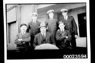 Ships and steamer crews, three ships officers stand in row behind three men in civilian clothes