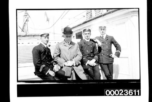 Ships and steamer crews, three men sitting and one standing on deck