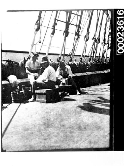 Ships and steamer crews, three men sitting on boxes and doing laundry