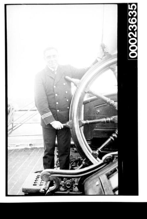 Ships and steamer crews, man in black uniform holding ship's wheel