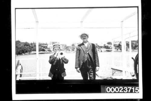 Man and boy playing trumpet on ship's deck