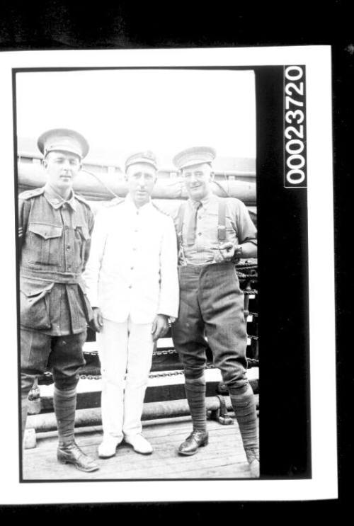 Three men standing on deck, two in military uniform