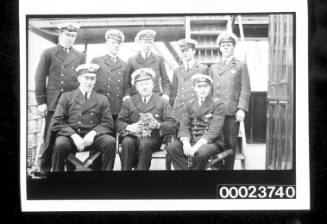 Group portrait of ship's officers, with the captain nursing a cat