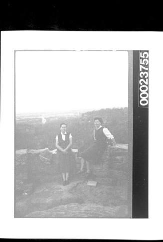 Two women sitting on a stone wall at lookout