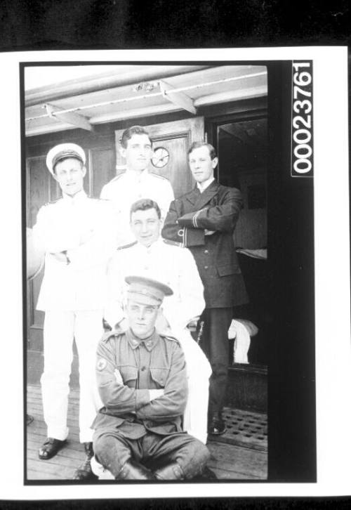 Soldier in khaki with four naval officers behind him