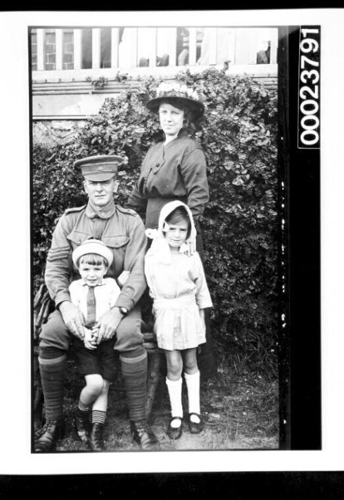 Soldier seated with youn boy and girl and woman standing next to him