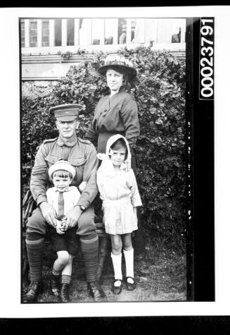 Soldier seated with youn boy and girl and woman standing next to him