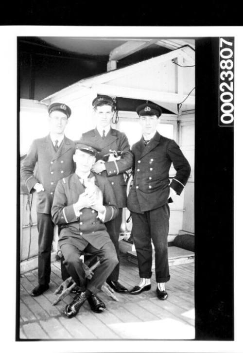 Four junior officers on a ship, one holding a kitten