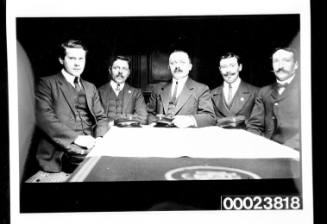 Five men seated around table