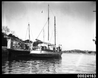 Stern and starboard view of a sailing ship moored to a second vessel at a wharf