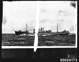 Portside view of a cargo vessel under steam in a harbour