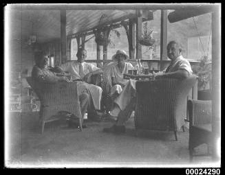 Image of three men and a woman seated on a verandah possibly on board SS TANDA