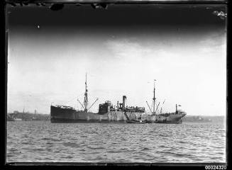 Portside view of a steam cargo ship at anchor in the harbour