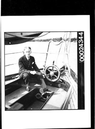 Harold Nossiter Snr in a suit at the cockpit of yacht SIRIUS after successfully sailing around the globe