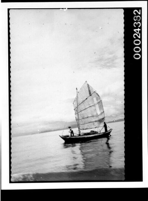 Two men on a native sailing craft on calm water