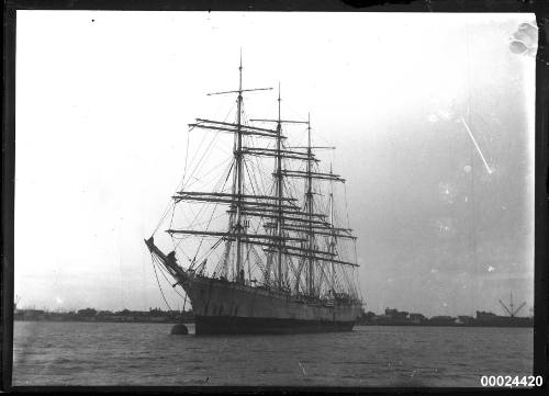 Portside view of a four-masted barque at anchor in a harbour