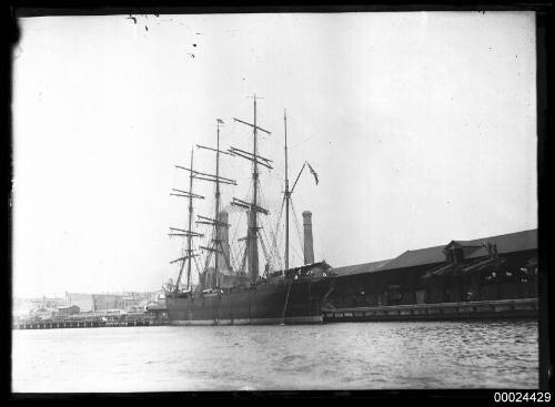 Portside view of a four-masted barque moored at a dockside