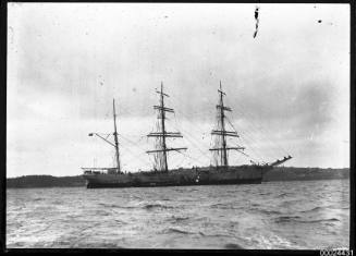 Starboard view of a three-masted barque anchored in a harbour