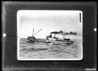 Single-funnel, two-masted merchant vessel under steam in a harbour