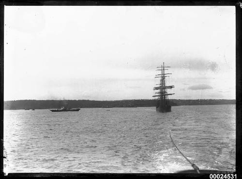 Frontal view of a fully rigged ship under tow in a harbour