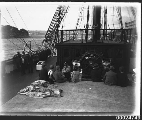 Civilians seated on a hatch in foreground on the deck of MAGDALENE VINNEN