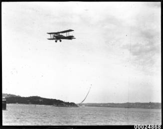 A single engine bi-plane in flight over Sydney Harbour