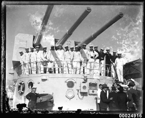 Crew members standing in front of the ship's gun turret on board the German cruiser KOLN