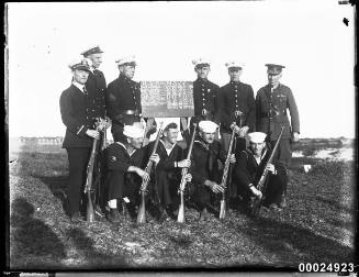 United States and Australian officers and sailors around a tally board
