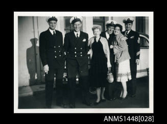 Naval officers and two women on a suburban street