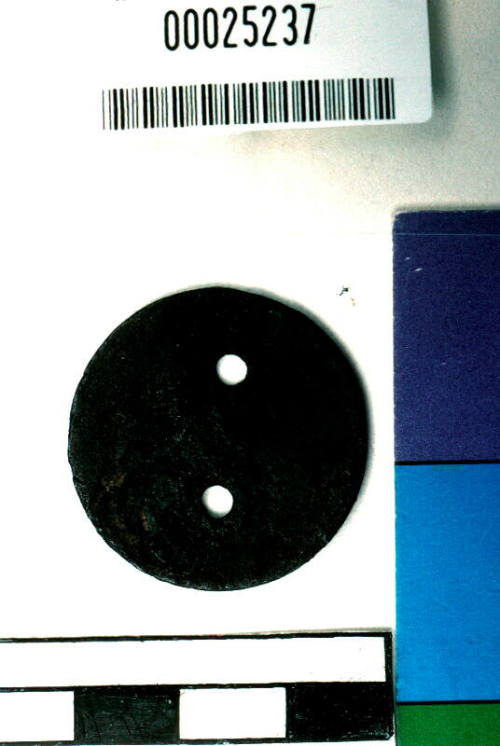 Corroded disc of metal with two pierced holes