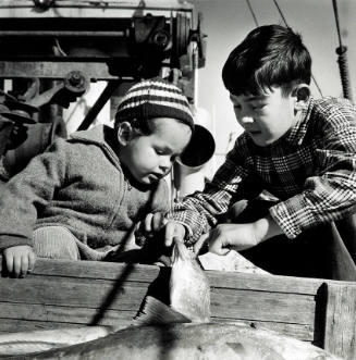 Photograph of two children looking at a dead fish
