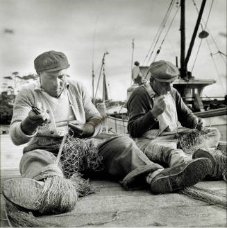 Photograph of men mending a net