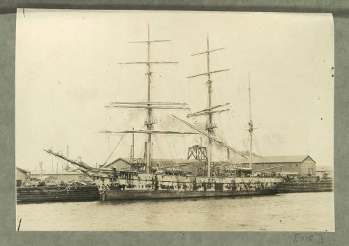 Full-rigged ship docked at a wharf - hull requiring painting