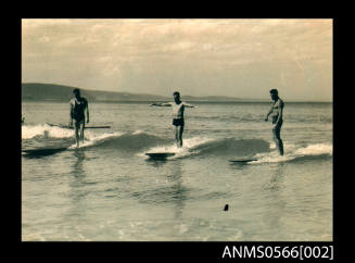 Three men, including William Cavanagh, surfing on long surfboards