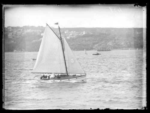 Gaff-rigged sloop with small cockpit area and seven visible crew