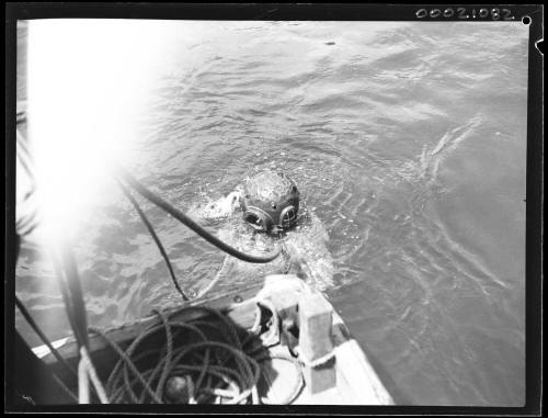 Unidentified diver partially submerged next to tug UNDINE