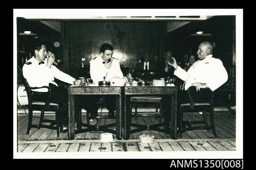Captain Dun seated at table with two men